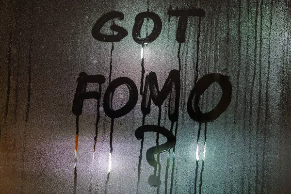 Pytanie dostał FOMO - strach przed brakiem - ręcznie napisane na mokrej powierzchni okna nocy z bliurry światła uliczne — Zdjęcie stockowe