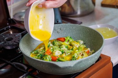 Kadın eli omlet pişirirken omlet kızarırken yumurta sarısı ekliyor.