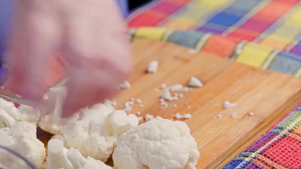 Elder caucasian woman cutting raw white cauliflower on bamboo cutting board — Stockvideo