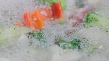 Kaynayan karnabahar, brokoli ve kırmızı çan biberinde köpük görünüyor. Yakın plan.