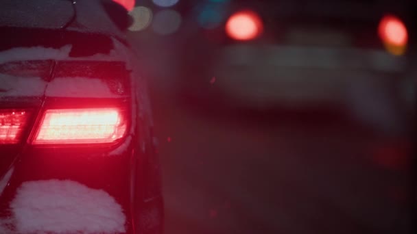 Червоний хвіст світло чорного автомобіля на нічній вулиці взимку снігопад — стокове відео