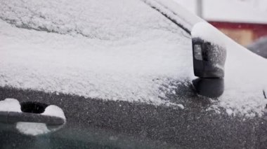 Kışın karla kaplı arabanın yakın görüntüsü. Kar yağışı, yavaş çekim.