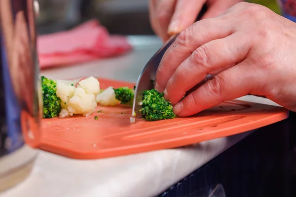 Close-up view dari wanita kulit putih tua tangan mengiris brokoli hijau dengan pisau dapur — Stok Foto