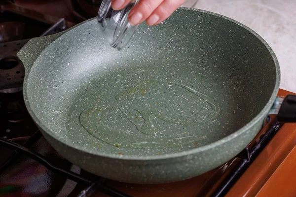 Wanita senior Kaukasia tangan menuangkan minyak sayur pada wajan panas kosong — Stok Foto