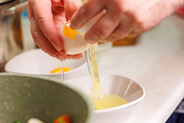 Tangan senior wanita kaukasia memecahkan telur ayam putih di atas mangkuk putih — Stok Foto
