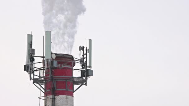 Теплова електростанція труба взимку з димом, парою та острівцями на телекомунікаційних антенах — стокове відео