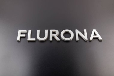 Flurona kelimesi parlak siyah arkaplanda gümüş metal harflerle yazılıydı.