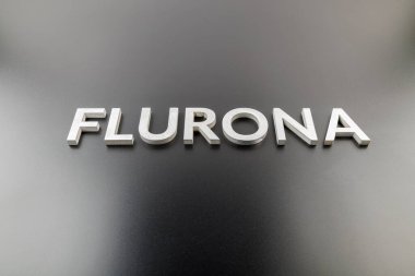 Flurona kelimesi parlak siyah arkaplanda gümüş metal harflerle yazılıydı.