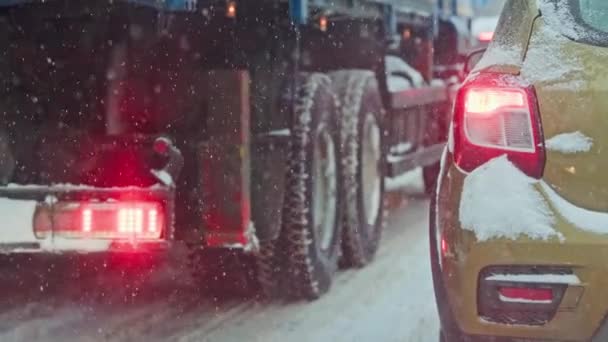 Сніговий покритий автомобіль хвіст світло в зимовий день біля вантажівки під час снігопаду — стокове відео