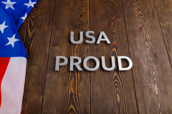 Palabras EE.UU. orgulloso establecido con letras de metal de plata en la superficie de madera marrón con la bandera de Estados Unidos de América — Foto de Stock