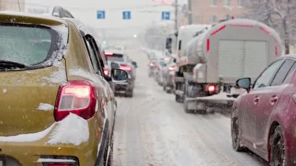 Besneeuwde auto achterlicht in de winter dag in het verkeer gestopt op kruispunt tijdens sneeuwval — Stockvideo