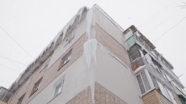 Grande isicles en ruso chrushevka esquina de construcción de 5 pisos en invierno nevada día — Vídeo de stock
