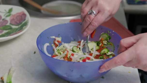 Mujer mayor blanca revolviendo ensalada de verduras en un tazón azul con tenedor, vista de cerca en las manos — Vídeos de Stock