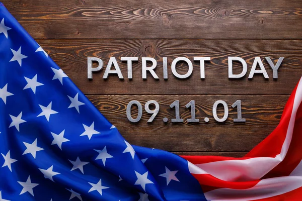The words patriot day laid with silver metal letters on wooden board surface with crumpled usa flag — Stock Photo, Image