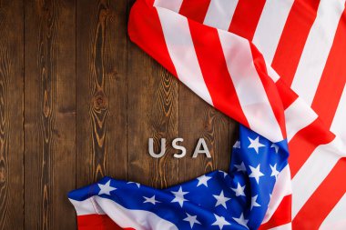 Amerika Birleşik Devletleri 'nin buruşuk bayrağı altında ahşap tahta yüzeyine gümüş metal harflerle yazılmış ABD sözcüğü.