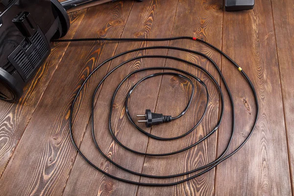 Cable de alimentación de la aspiradora negra en la superficie de madera — Foto de Stock