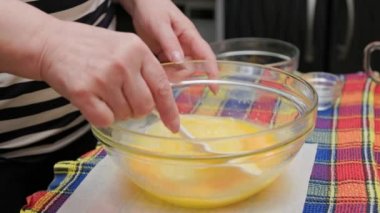 Beyaz plastik spatulayla kaseye tatlı sıvı hamur karıştıran beyaz kadın.