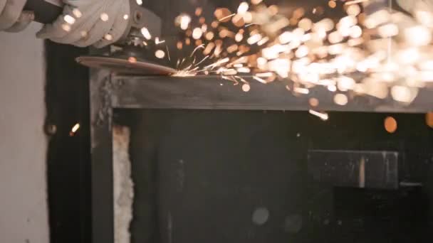 Ruční čištění svařovaných švů s úhlovou bruskou s klapkovým kotoučem na svařované kovové konstrukci detailní záběr s dlouhými jiskřícími stopami, pomalý pohyb — Stock video