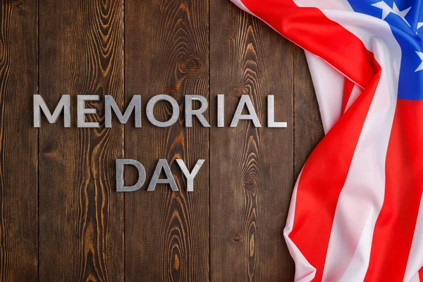 The words memorial day laid with silver metal letters on wooden board surface with crumpled usa flag — Zdjęcie stockowe