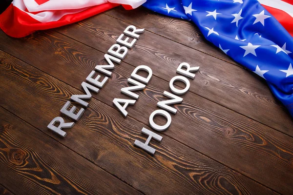 Palabras recuerde y honor establecido con letras de metal plateado sobre fondo de madera con bandera de EE.UU. en el lado derecho — Foto de Stock