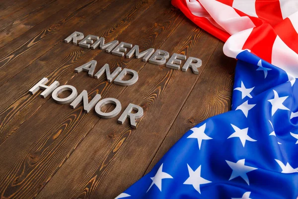 Woorden onthouden en eren gelegd met zilveren metalen letters op houten achtergrond met USA vlag aan de rechterkant Stockfoto