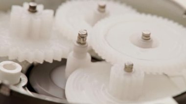 Beş plastik dişli, küçük bir küçültme dişlisinin içinde karşılıklı ağ şeklinde döner.