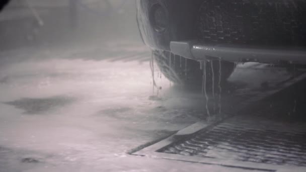 Araba tamponundan damlayan deterjanlı su. Kapalı alanda oto yıkama işlemi. Seçici odaklı ve yavaş çekimde yakın çekim görünümü. — Stok video