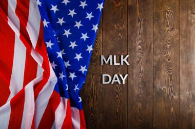 MLK günü, ahşap yüzeyinde gümüş metal harflerle ve sol tarafında buruşuk Amerikan bayrağıyla yazılıydı.