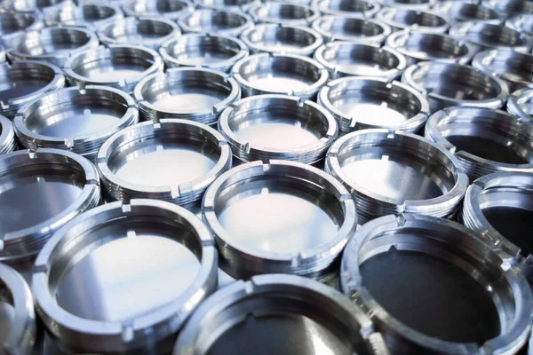 Shiny metal rings after turning and milling, silver colored parts on flat steel surface close-up full frame background — Stock Fotó