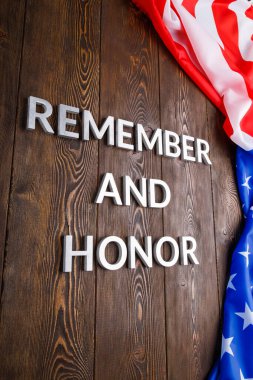 Kelimeler unutmayın ve onurlandırın gümüş metal harflerle ahşap arka planda ABD bayrağı sağ tarafta