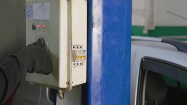 hand in black glove ligting silver car on elevator in auto service station.