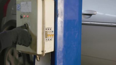 hand in black glove ligting silver car on elevator in auto service station.