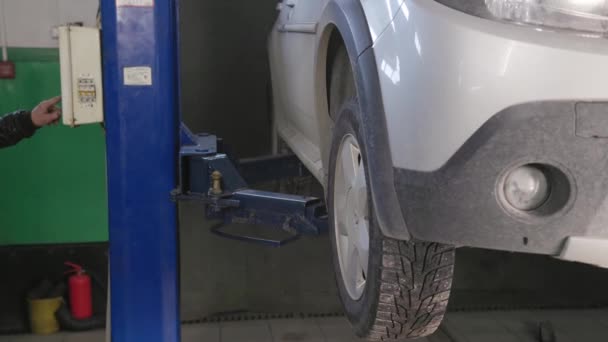 Worker lowering silver Renault Sandero Stepway in auto repair shop — Wideo stockowe