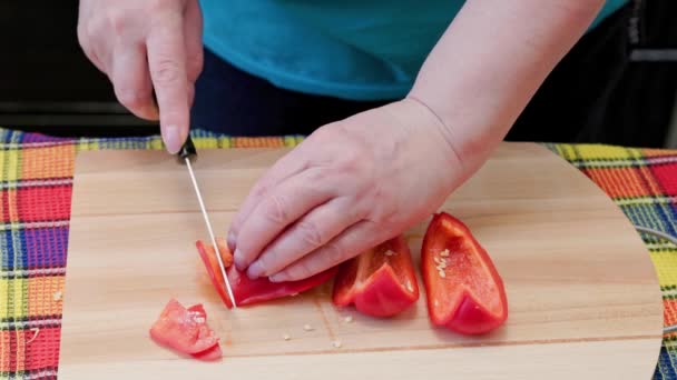 Senior caucasian woman cut sweet red bell pepper on wooden cutting board — Stok video