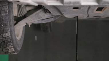 used motor oil flowing down from engine of lifted vehicle during oil change