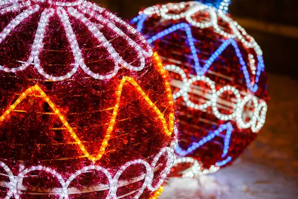 Decorative outdoor cristmas light balls with glowing neon wires and red artificial fir-needles — Stockfoto
