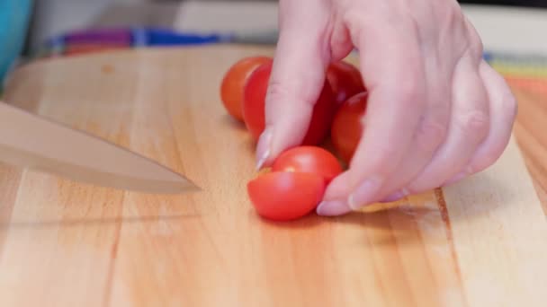 Senior caucasian woman cut red cherry tomatoes on wooden cutting board — Video