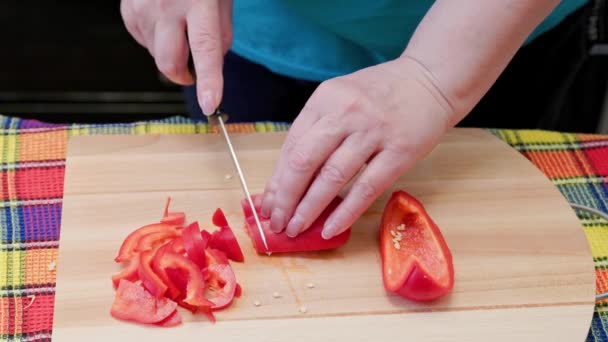 Senior caucasian woman cut sweet red bell pepper on wooden cutting board — Wideo stockowe