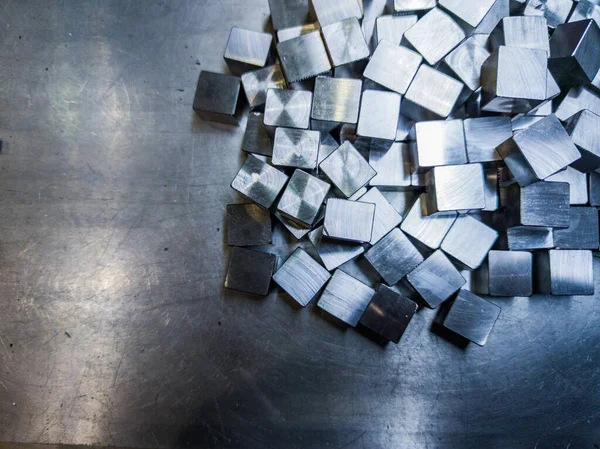 Pile of small machined shiny steel cubes on metal surface — Stockfoto