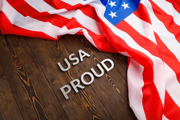 Palabras EE.UU. orgulloso establecido con letras de metal de plata en la superficie de madera marrón con la bandera de Estados Unidos de América — Foto de Stock