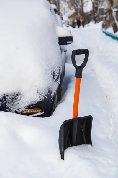 Plastic snow shovel in front of snow-covered car at winter morning —  Fotos de Stock