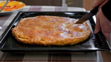 caucasuan hands slicing freshly baked domestic ossetian pie on with knife