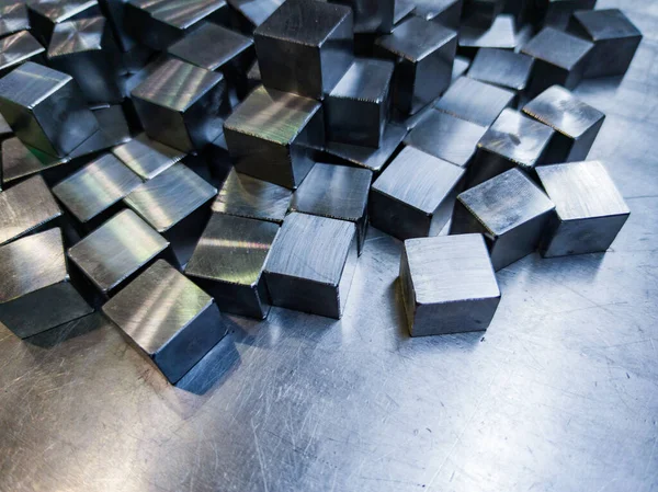 Pile of small machined shiny steel cubes on metal surface — Photo