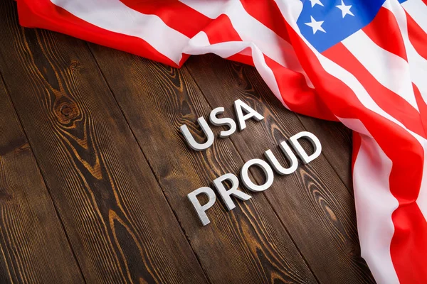 Palabras EE.UU. orgulloso establecido con letras de metal de plata en la superficie de madera marrón con la bandera de Estados Unidos de América — Foto de Stock