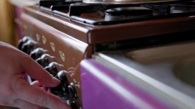 hand of caucasian man igniting brown domestic gas stove and then turning it off