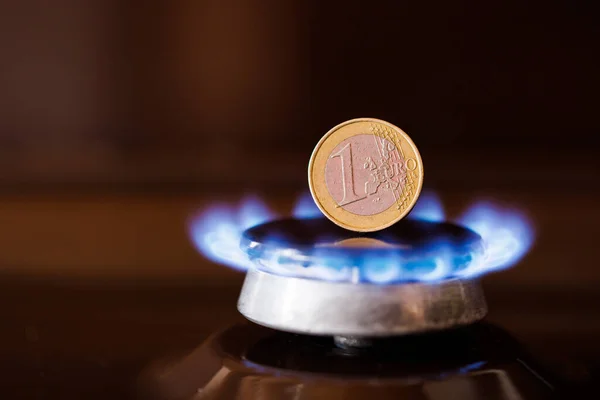 Gas stove burner with one euro coin standing vertically on top, burning natural gas with blue flame — Stock Photo, Image