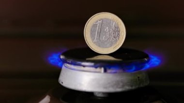 gas stove burner with one euro coin standing vertically on top, burning gas