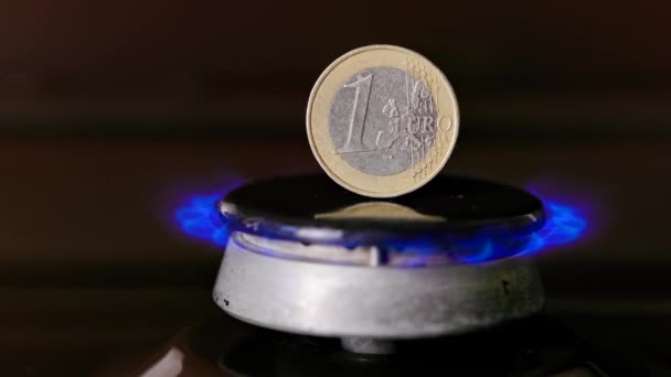 Gas stove burner with one euro coin standing vertically on top, burning gas — Stok video