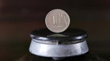gas stove burner with russian ruble standing vertically on top, burning gas