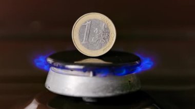 gas stove burner with one euro coin standing vertically on top, burning gas